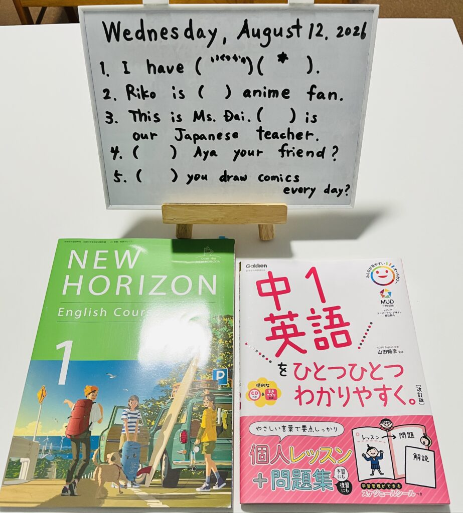 中学生英語コースで使用するNEW HORIZONと問題集、ホワイトボードでの英文練習